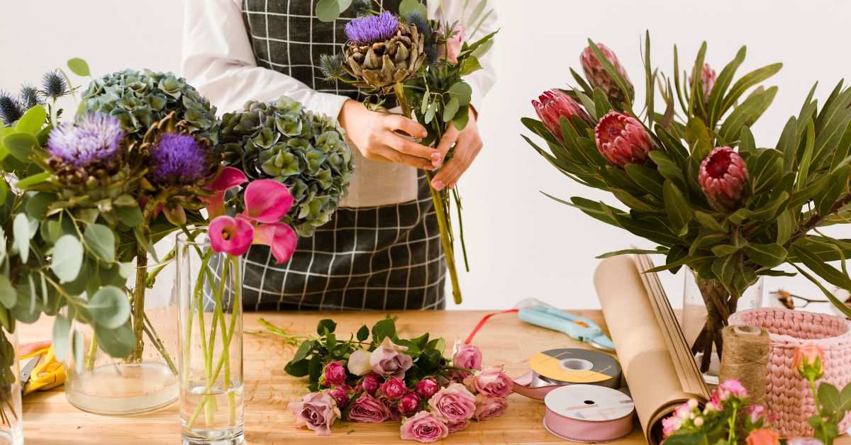 A woman's arranging many kinds of flower in to the transparent vases 